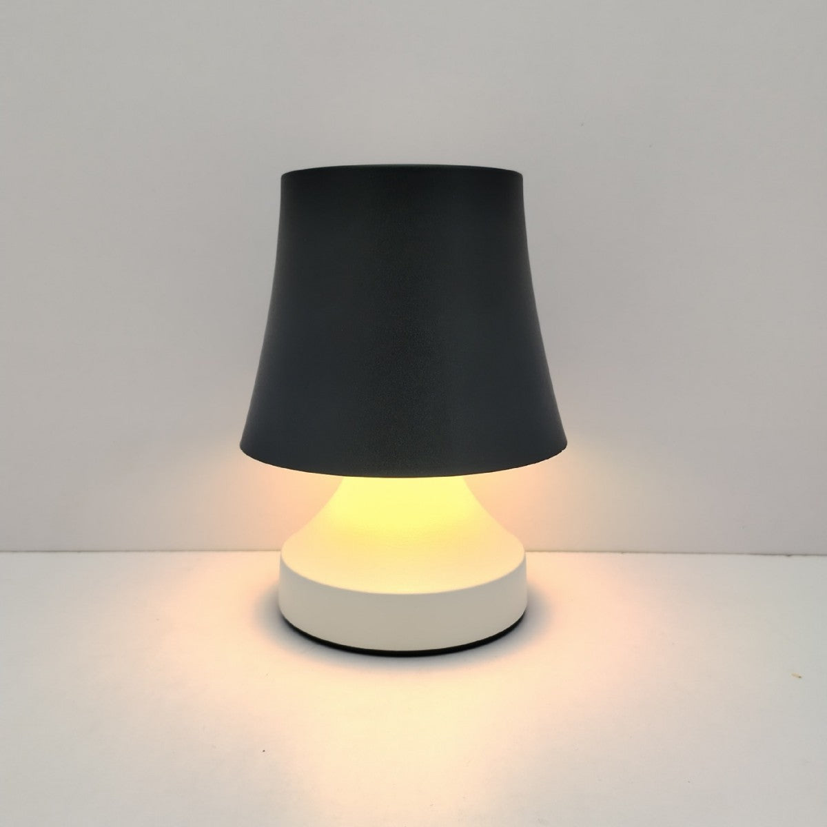 Small lamp with a black shade and white base on a light gray background