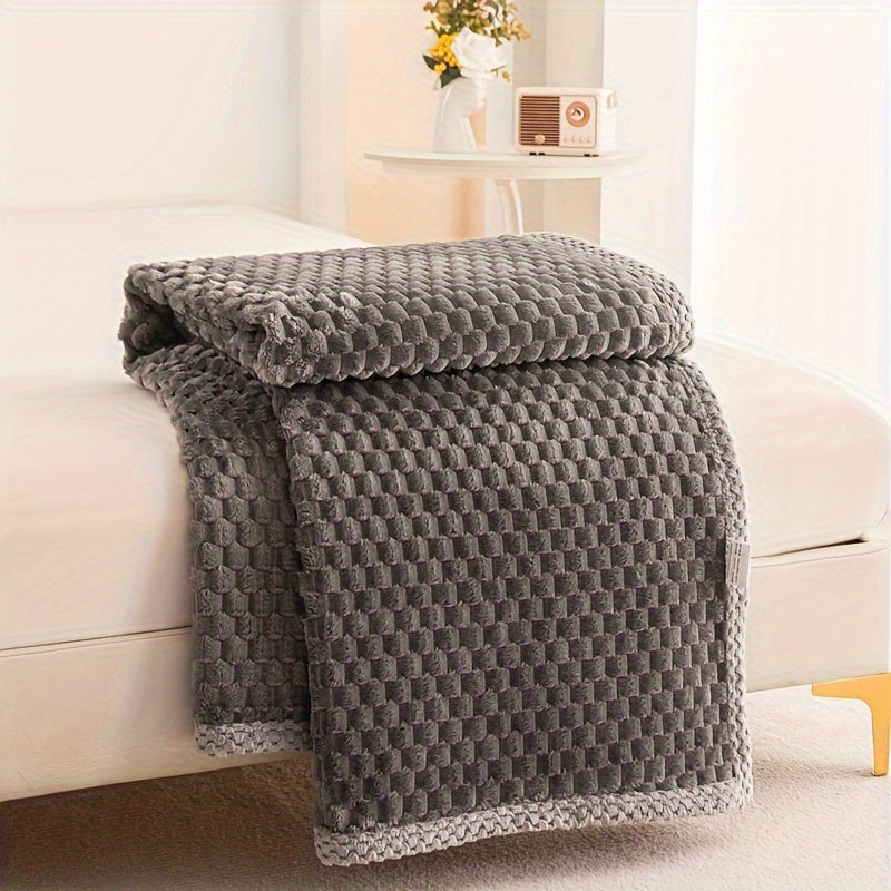 Gray textured blanket draped over a white sofa in a bright room.
