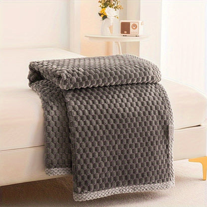 Gray textured blanket draped over a white sofa in a bright room.