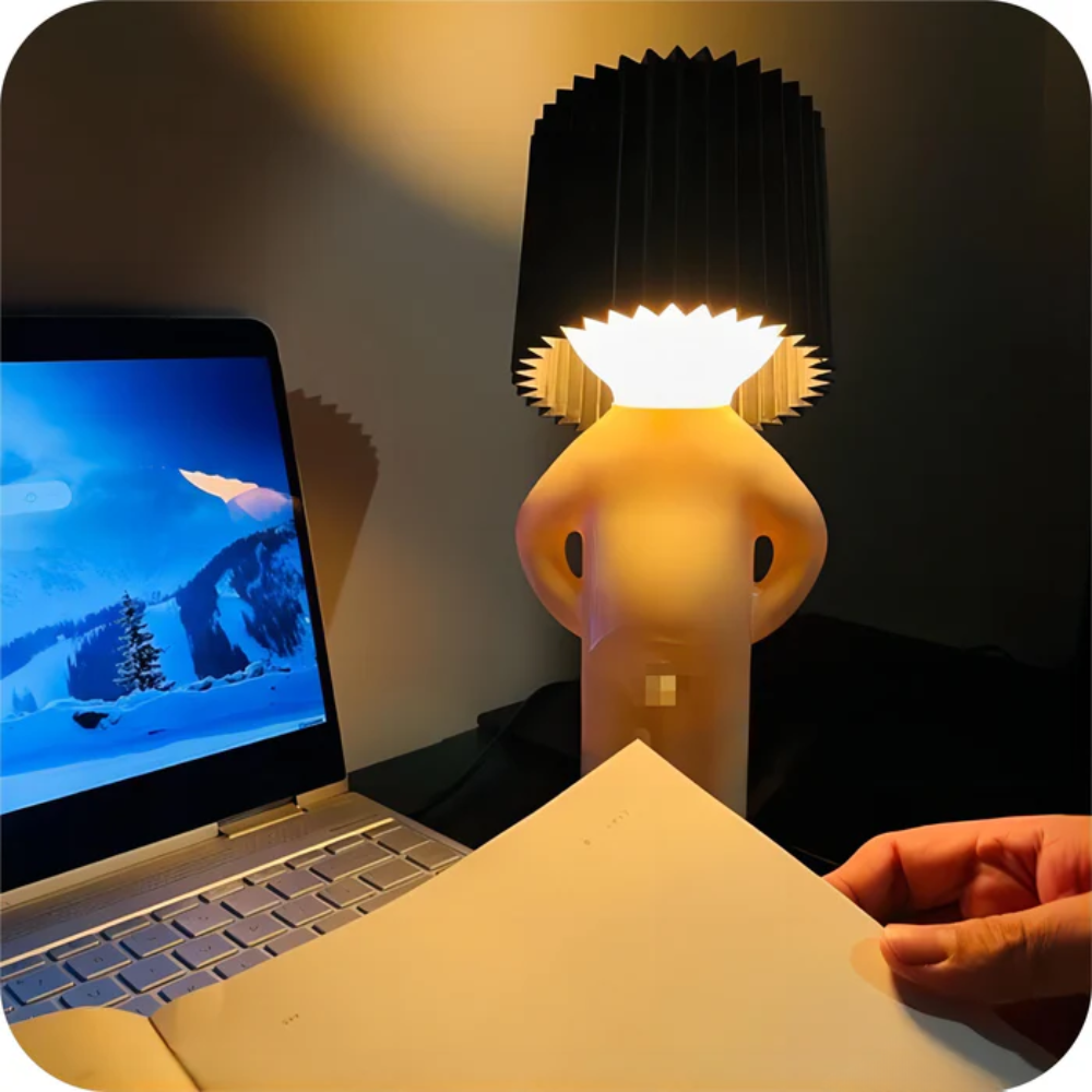 Person holding a small lamp next to a laptop on a desk