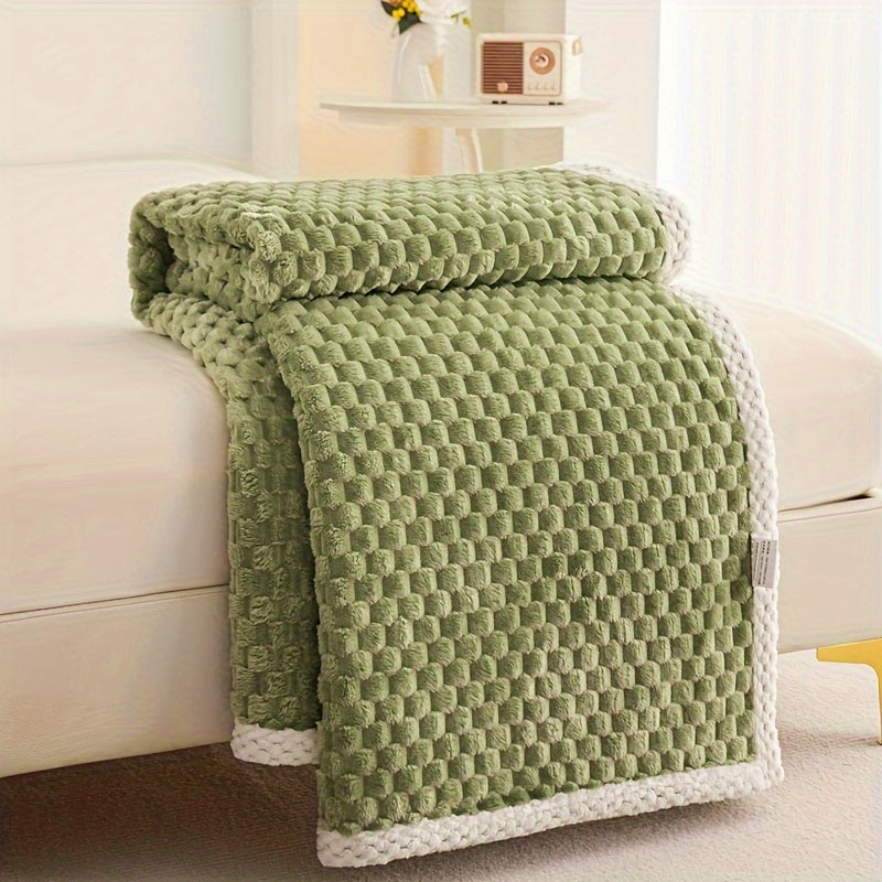 Green textured blanket draped over a beige sofa in a living room setting.