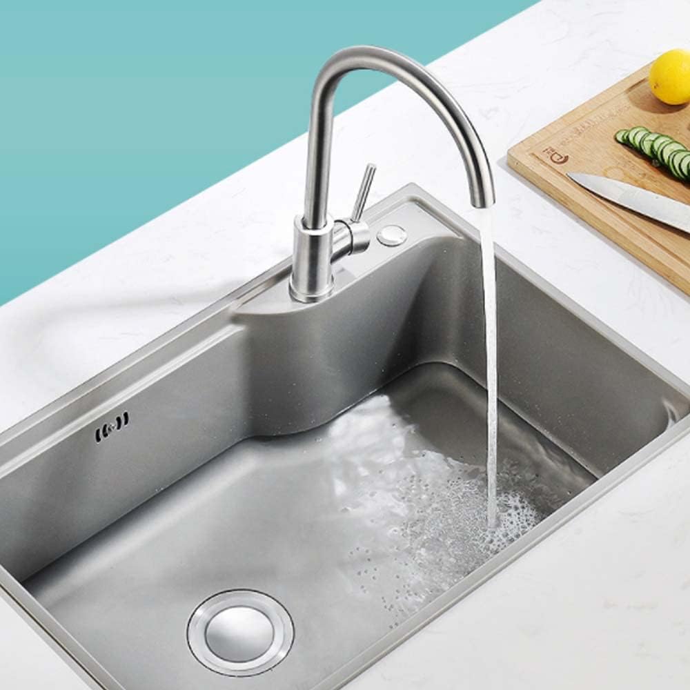Stainless steel kitchen sink with running water on a white countertop.