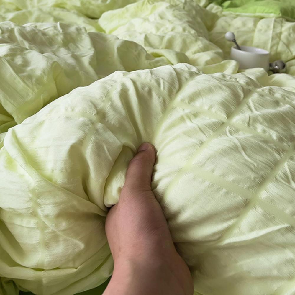 Light green fabric with a hand holding it, showing texture and color.