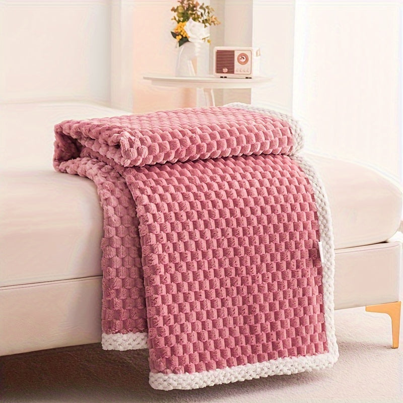 Pink textured blanket draped over a beige sofa in a living room setting.