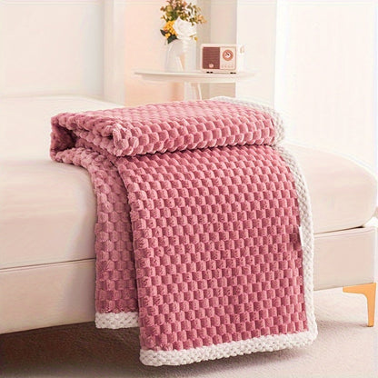 Pink textured blanket draped over a beige sofa in a living room setting.