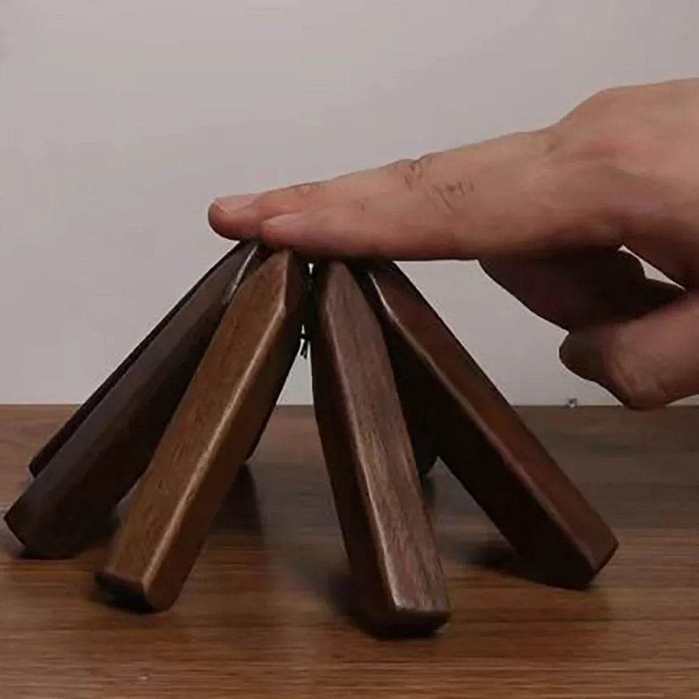 Wooden coasters stacked on a wooden surface with a hand lifting one coaster.