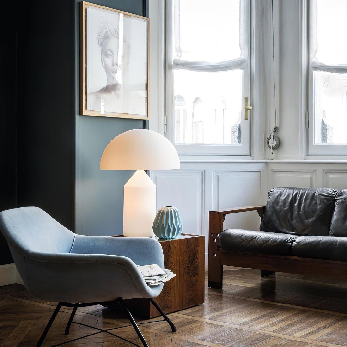 Modern living room with a gray armchair, lamp, and sofa.