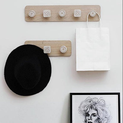 Wooden wall hook with a black hat and white bag on a white wall.