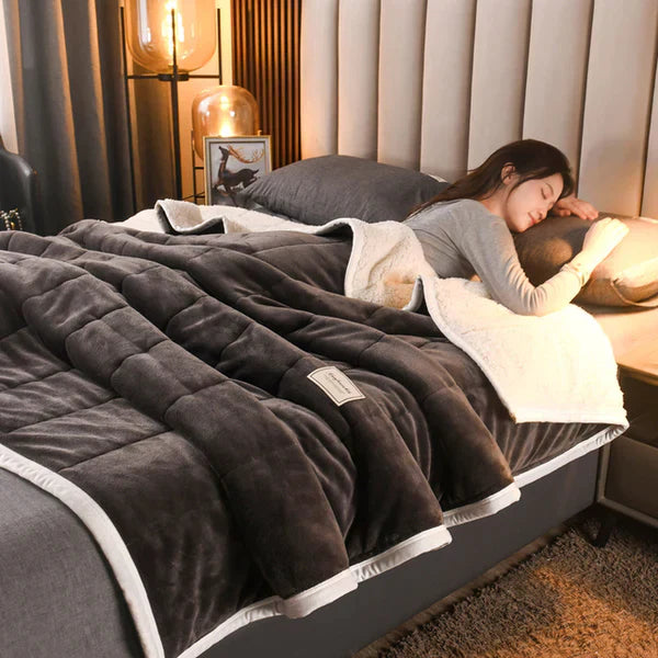 Woman lying on a bed with a dark gray comforter in a cozy bedroom setting.