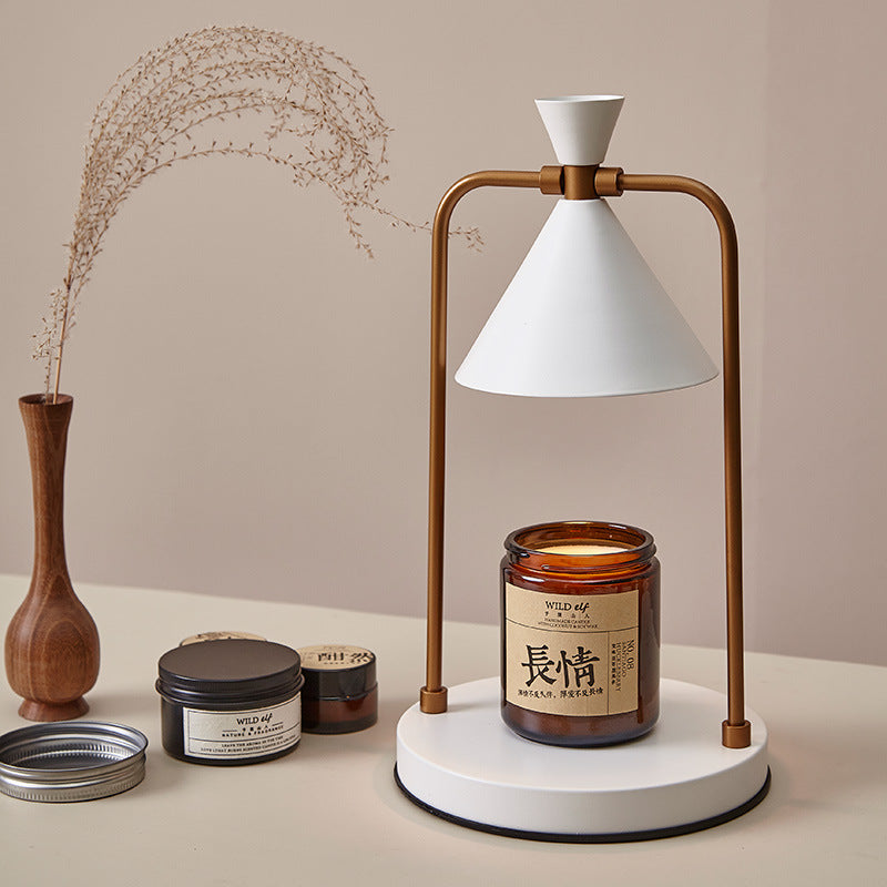 Decorative setup with a lamp, candles, and a vase on a beige surface.