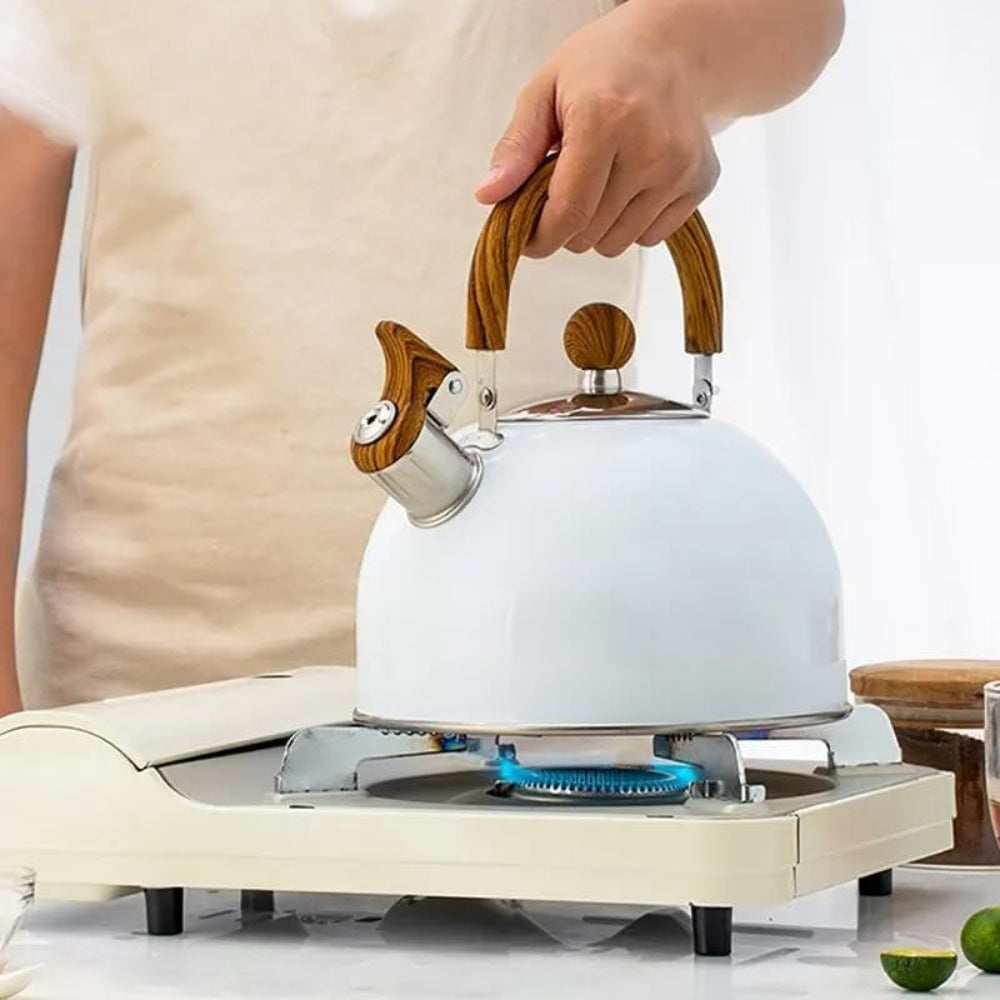 White kettle with wooden handle being used on a portable stove