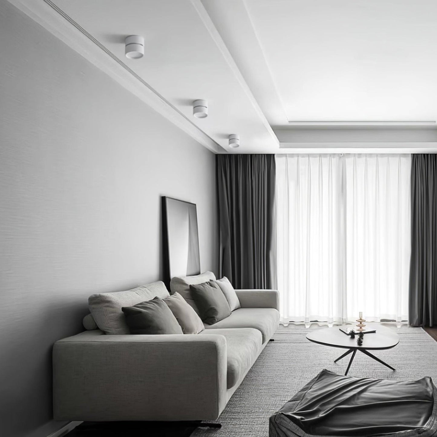 Modern living room with a gray sofa, coffee table, and large windows.
