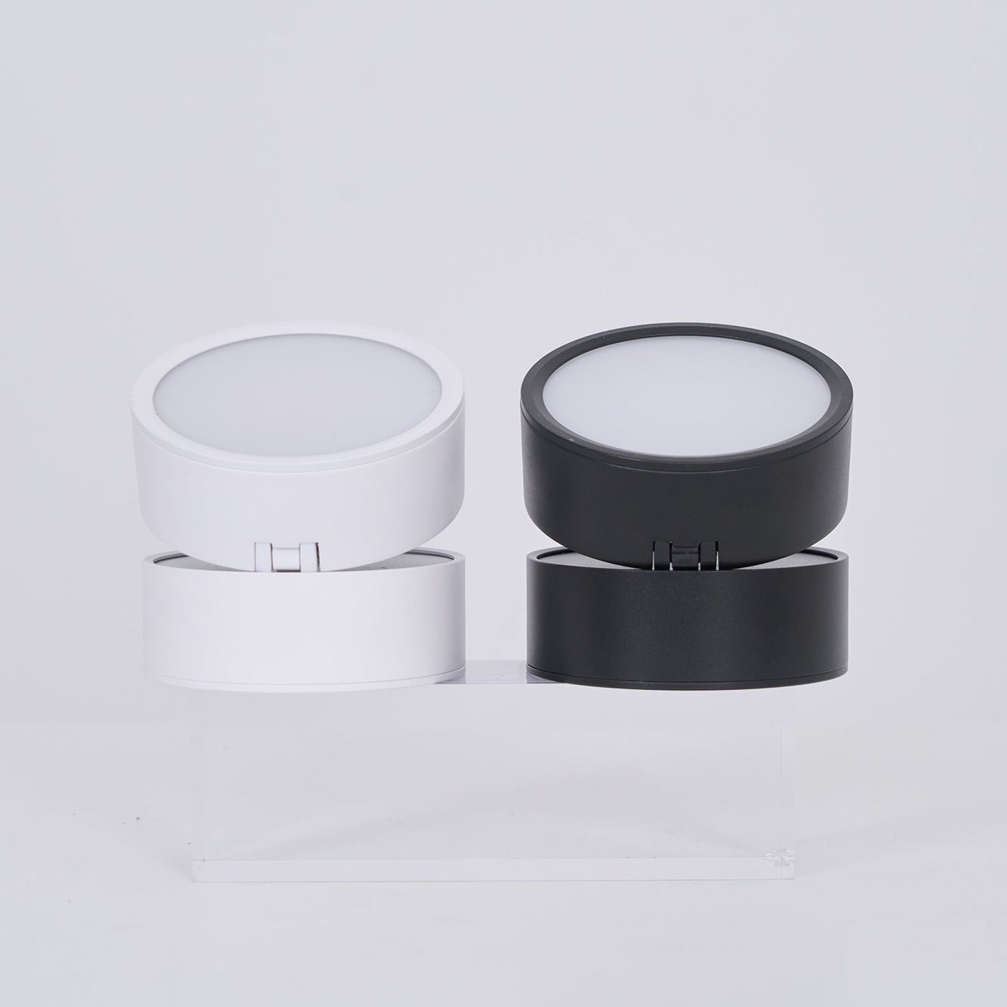 Two cylindrical containers, one white and one black, on a light gray background.