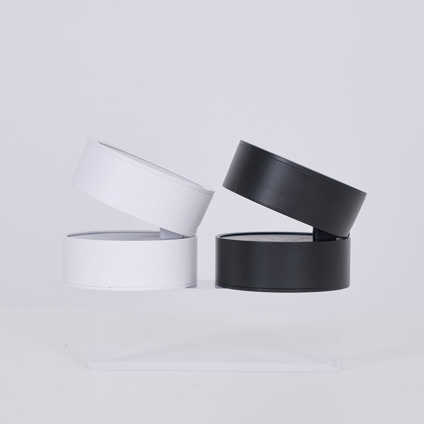 Two black cylindrical containers with clear lids on a light gray background