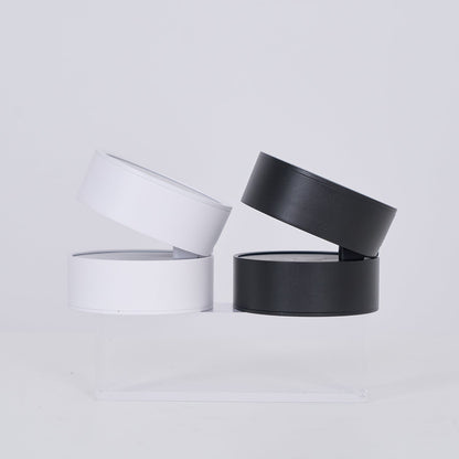 Two black cylindrical containers with clear lids on a light gray background