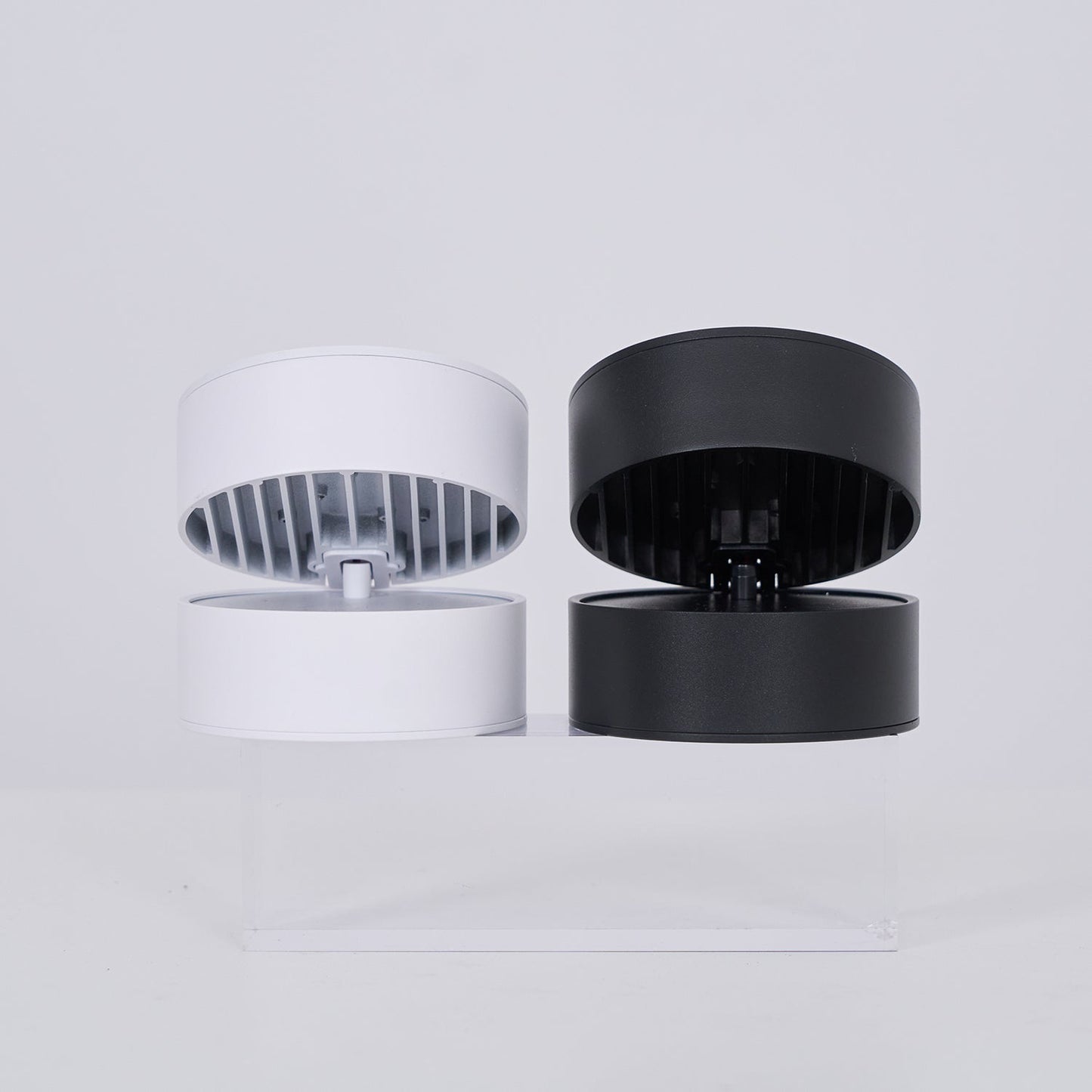 Two cylindrical light, one white and one black, on a light gray background.