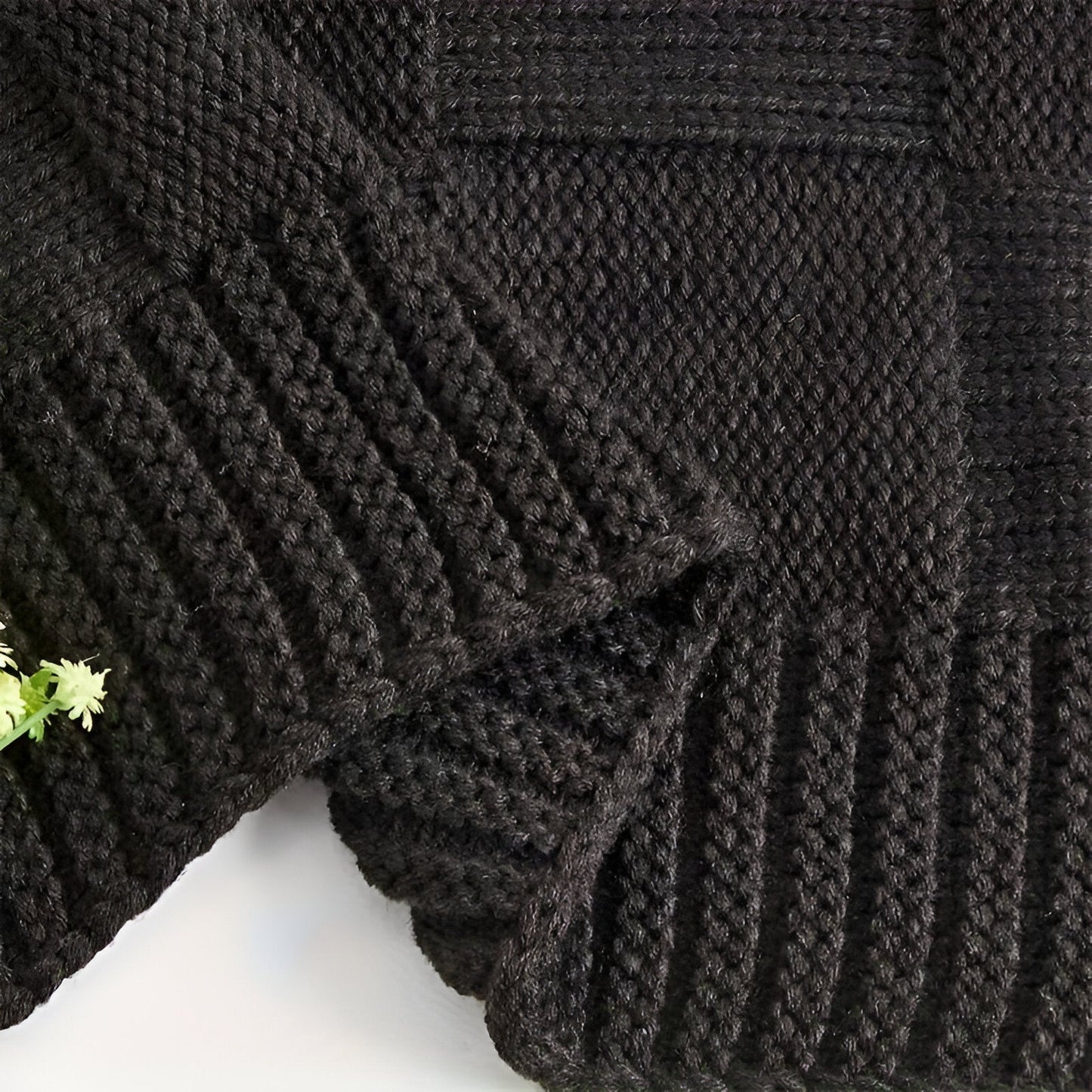 Close-up of a dark gray knitted sweater with a textured pattern on a white background