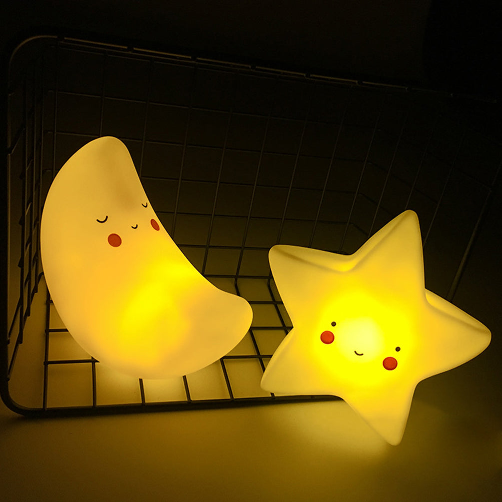 Two glowing moon and star-shaped night lights on a dark background