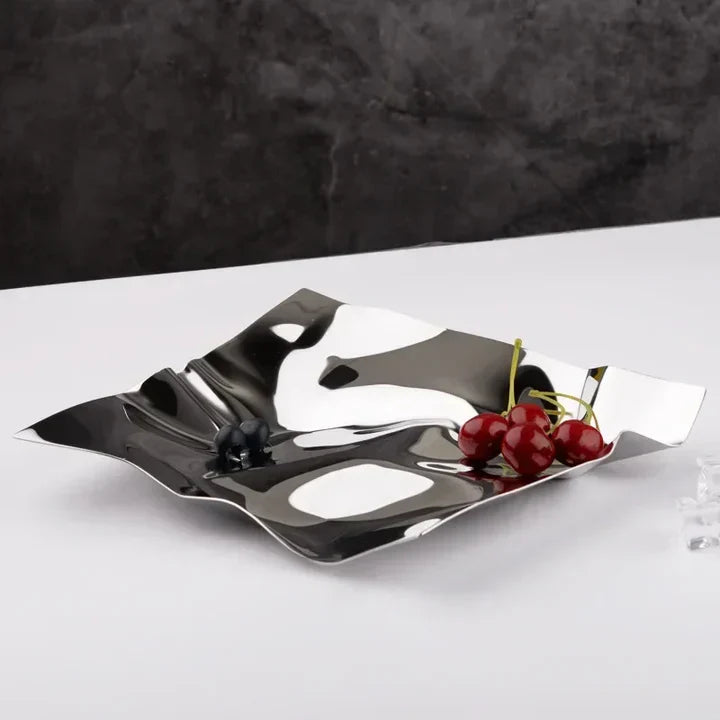Silver decorative tray with cherries on a white surface