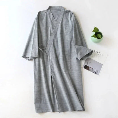 Gray robe on a white surface with a small plant and card in the background