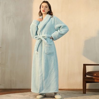 Woman wearing a light blue robe in a room with wooden flooring and a chair.