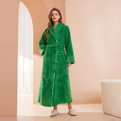 Woman wearing a green robe in a minimalistic room with a beige wall and white floor.