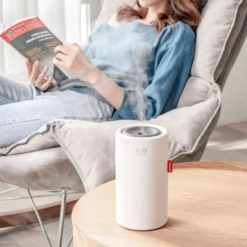 Person reading a book with a humidifier on a table in the foreground