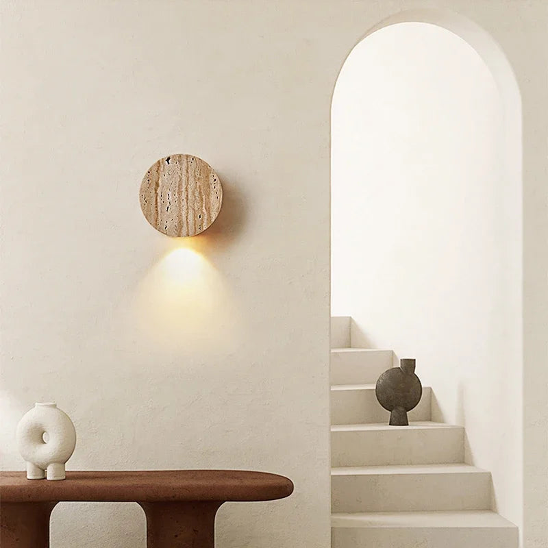 Modern interior with a wall-mounted light fixture, table, and staircase.