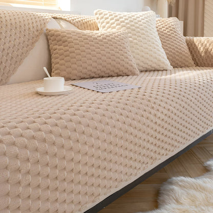 Beige textured sofa with cushions and a cup on a wooden floor.