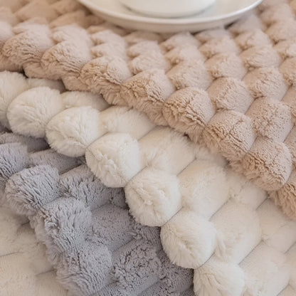 Textured woven rug with pom-pom pattern in neutral colors.