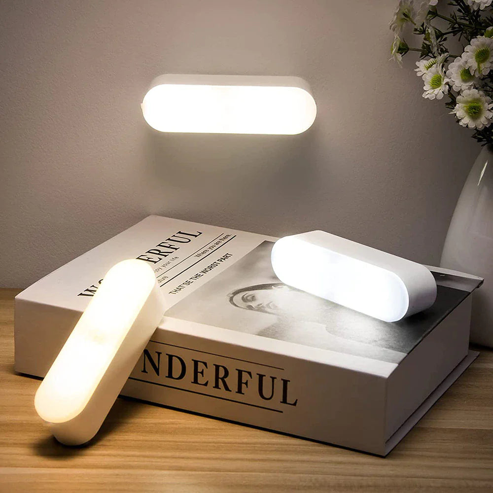 Modern wall and table lamps on a book with 'WONDERFUL' text, next to a vase with flowers.
