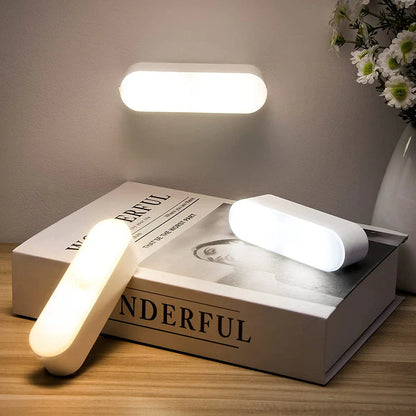 Modern wall and table lamps on a book with 'WONDERFUL' text, next to a vase with flowers.