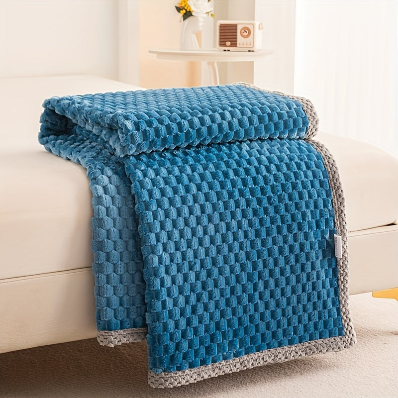 Blue textured blanket draped over a white couch in a cozy living room setting.