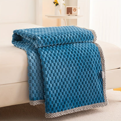 Blue textured blanket draped over a white couch in a cozy living room setting.