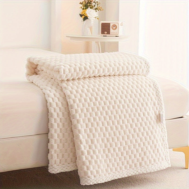 Beige textured blanket draped over a white sofa in a bright room.