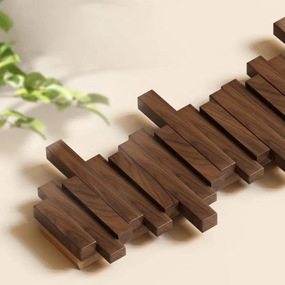 Wooden coasters arranged in a zigzag pattern on a light surface with a plant in the background.