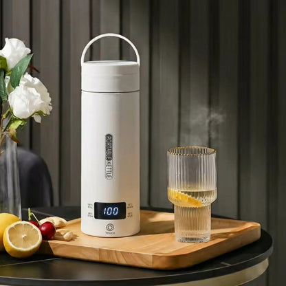 White electric kettle on a wooden tray with a glass of lemon water and flowers in the background.