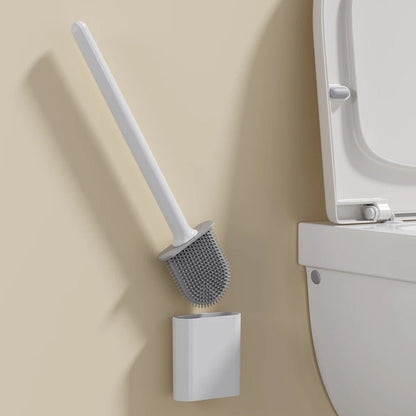 White toilet brush with holder against a beige wall next to a white toilet.