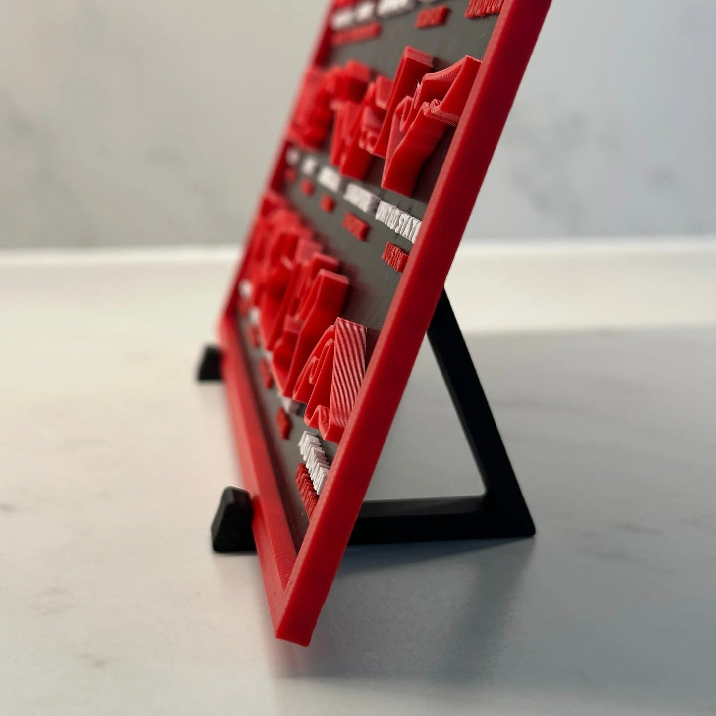 Red and black electronic device on a stand with a blurred background