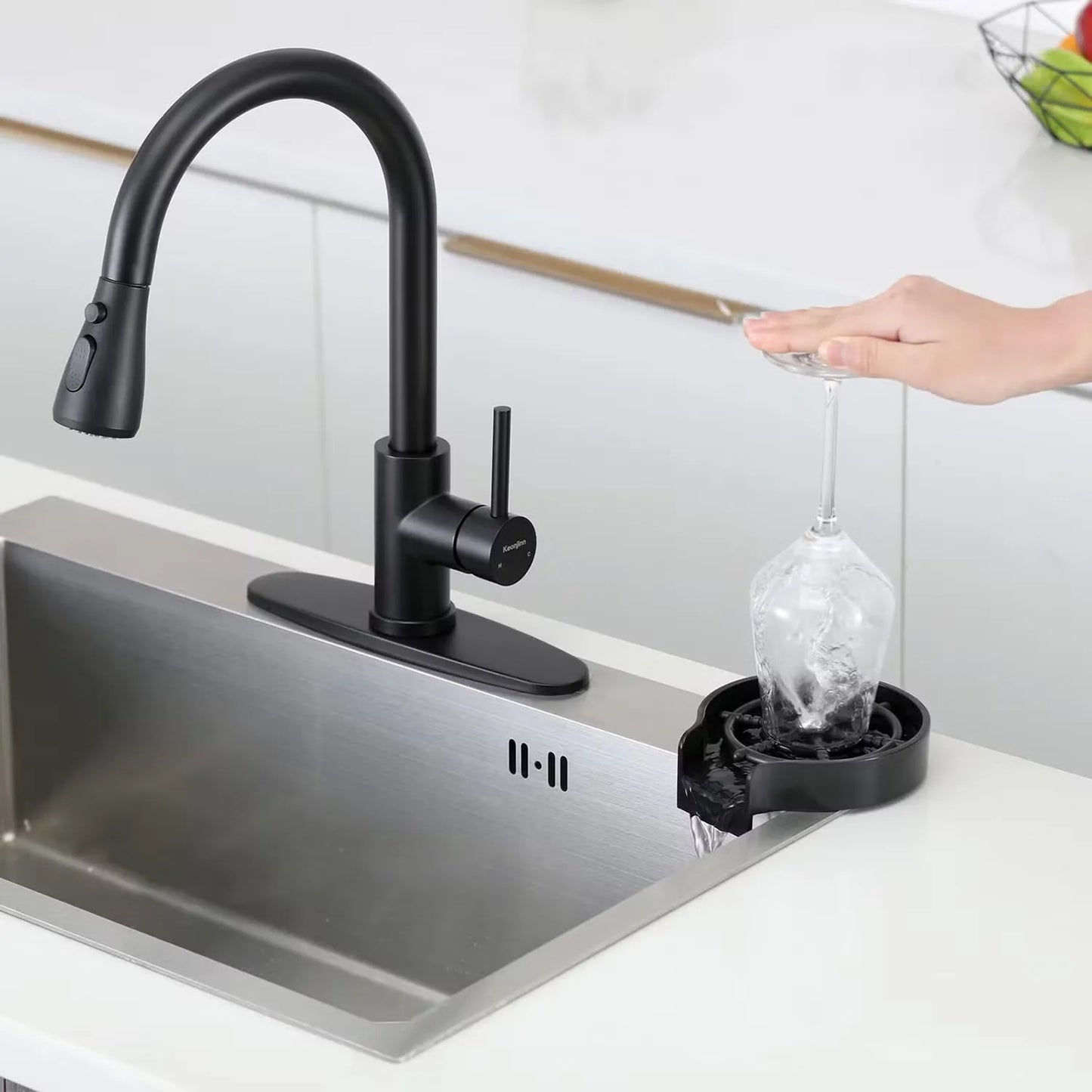 Black kitchen faucet with a sink and a hand holding a glass under running water.