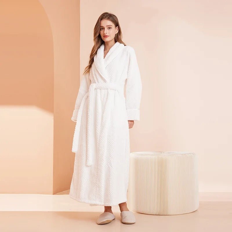 Woman wearing a white robe standing against a beige background