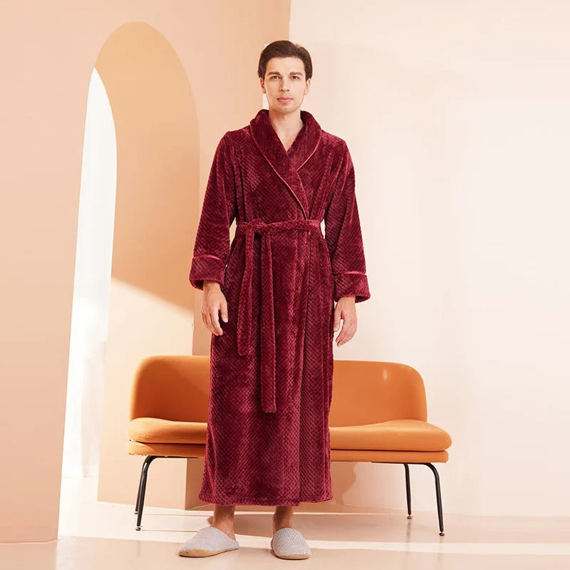 Man wearing a burgundy robe standing in a room with an orange chair and beige walls.