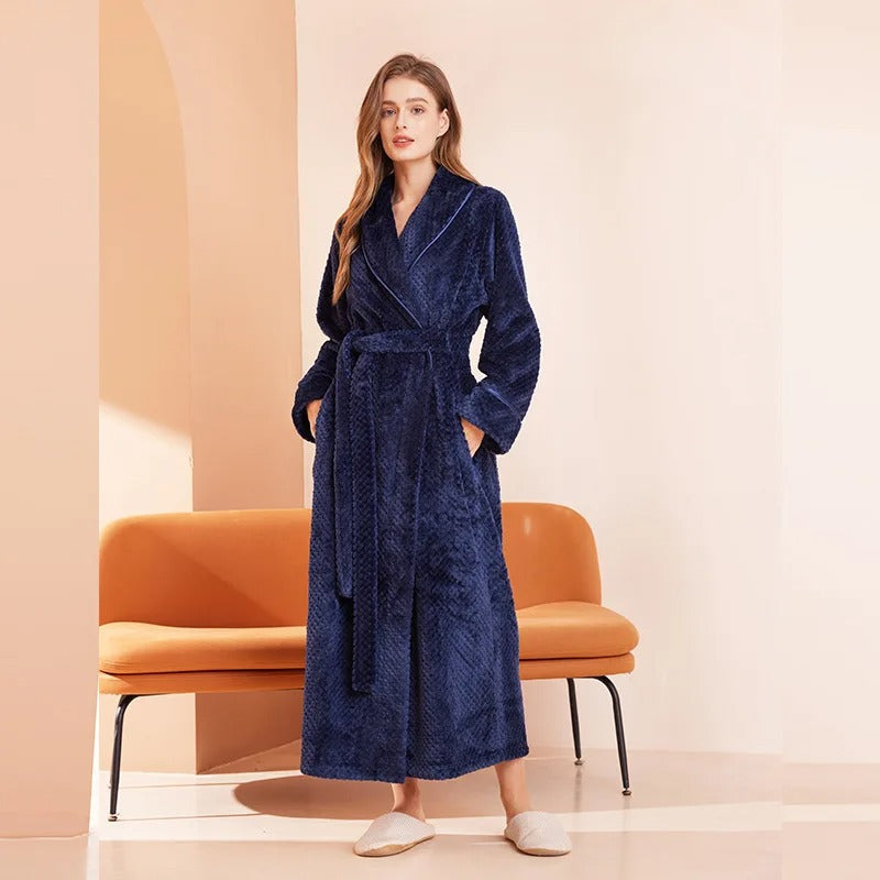 Woman wearing a blue robe standing in a minimalistic room with an orange chair.