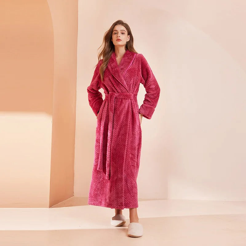 Woman wearing a pink robe standing against a beige background