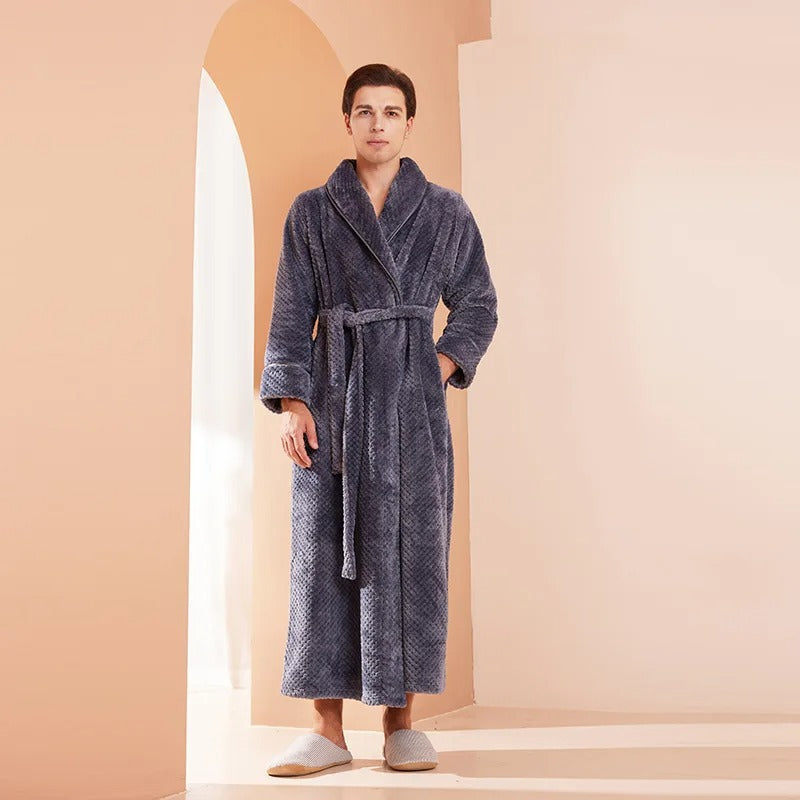 Man wearing a blue robe standing in a softly lit room with a warm color palette.