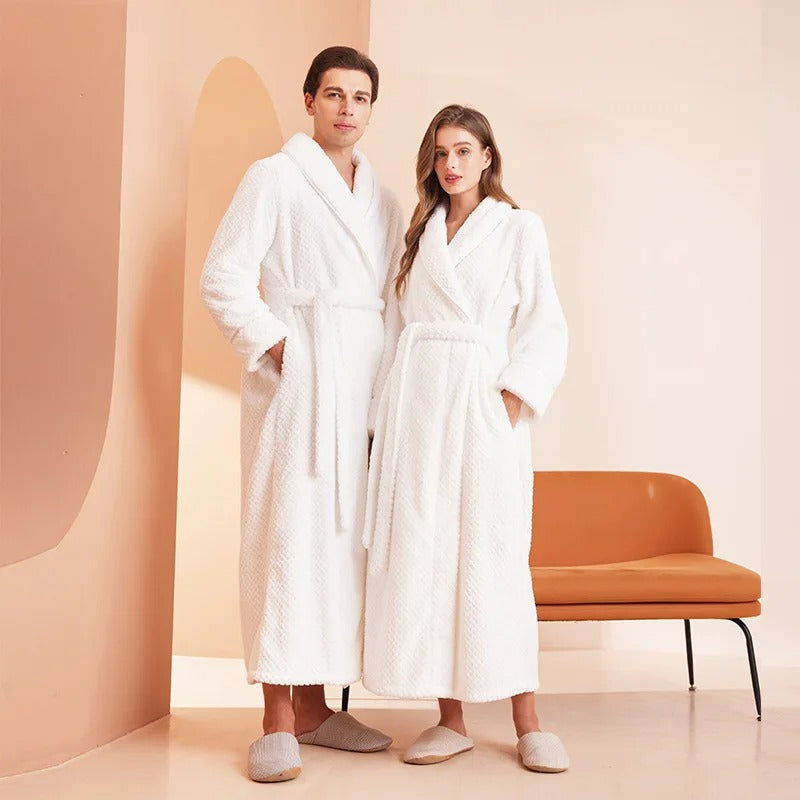 Two people wearing white robes standing in a room with a chair and abstract wall.