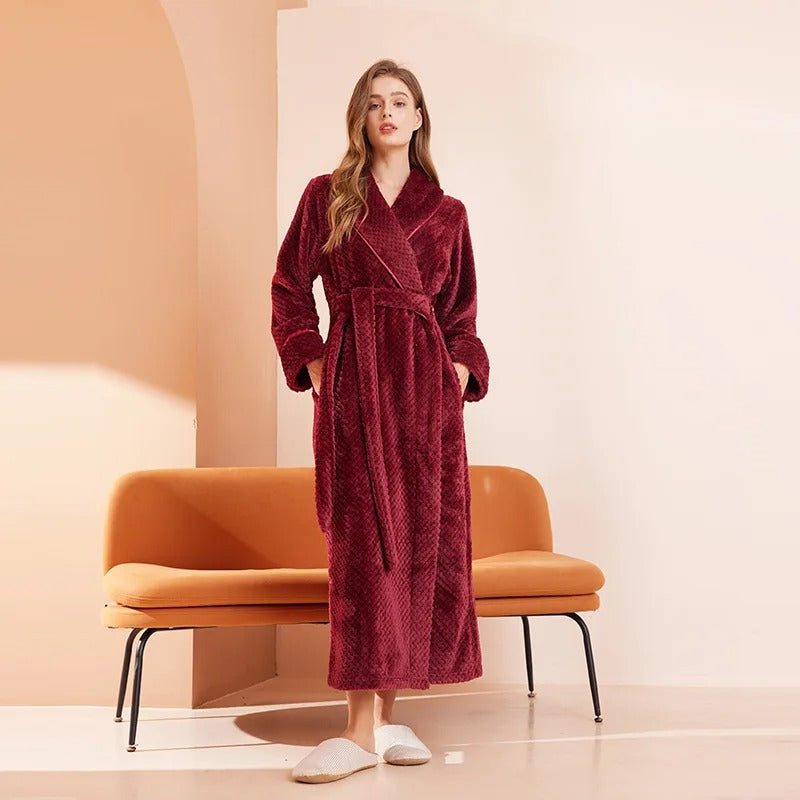 Woman wearing a red robe standing in a minimalistic room with an orange chair.