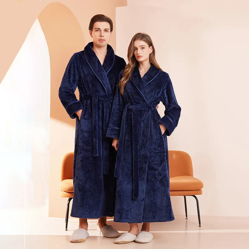 Two people wearing navy blue robes standing in a room with a beige wall and orange chair.