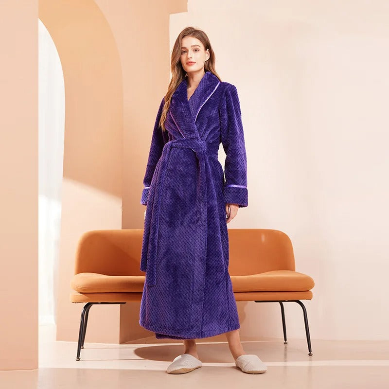 Woman wearing a purple robe standing in a room with a brown chair.
