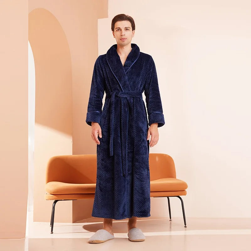 Man wearing a blue robe standing in a minimalistic room with an orange chair.